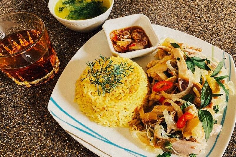 Đĩa cơm gà Đà Nẵng hấp dẫn với cơm vàng, thịt gà, rau sống và nước chấm.